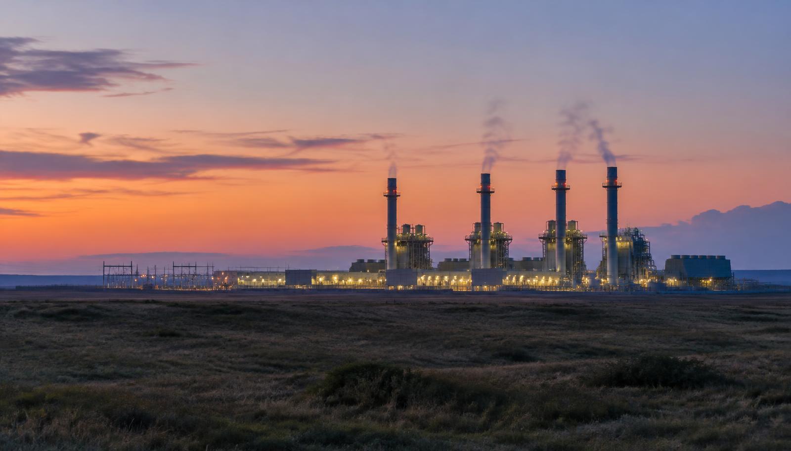 A natural gas power plant seen from a distance at twilight
